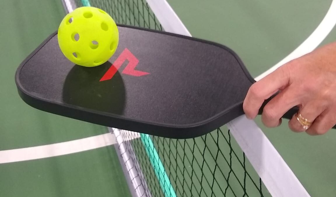 One pickleball paddle held by a hand.